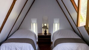 A bedroom with two beds, wooden beams, a ceiling light, and a nightstand with a lamp. - Posada del Maple - Hostel (Quito)