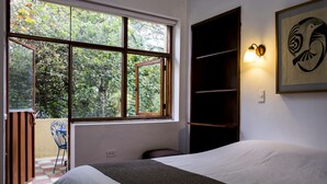 A bedroom with a large window, a bed, a chair, and a wall-mounted shelf. - Posada del Maple - Hostel (Quito)