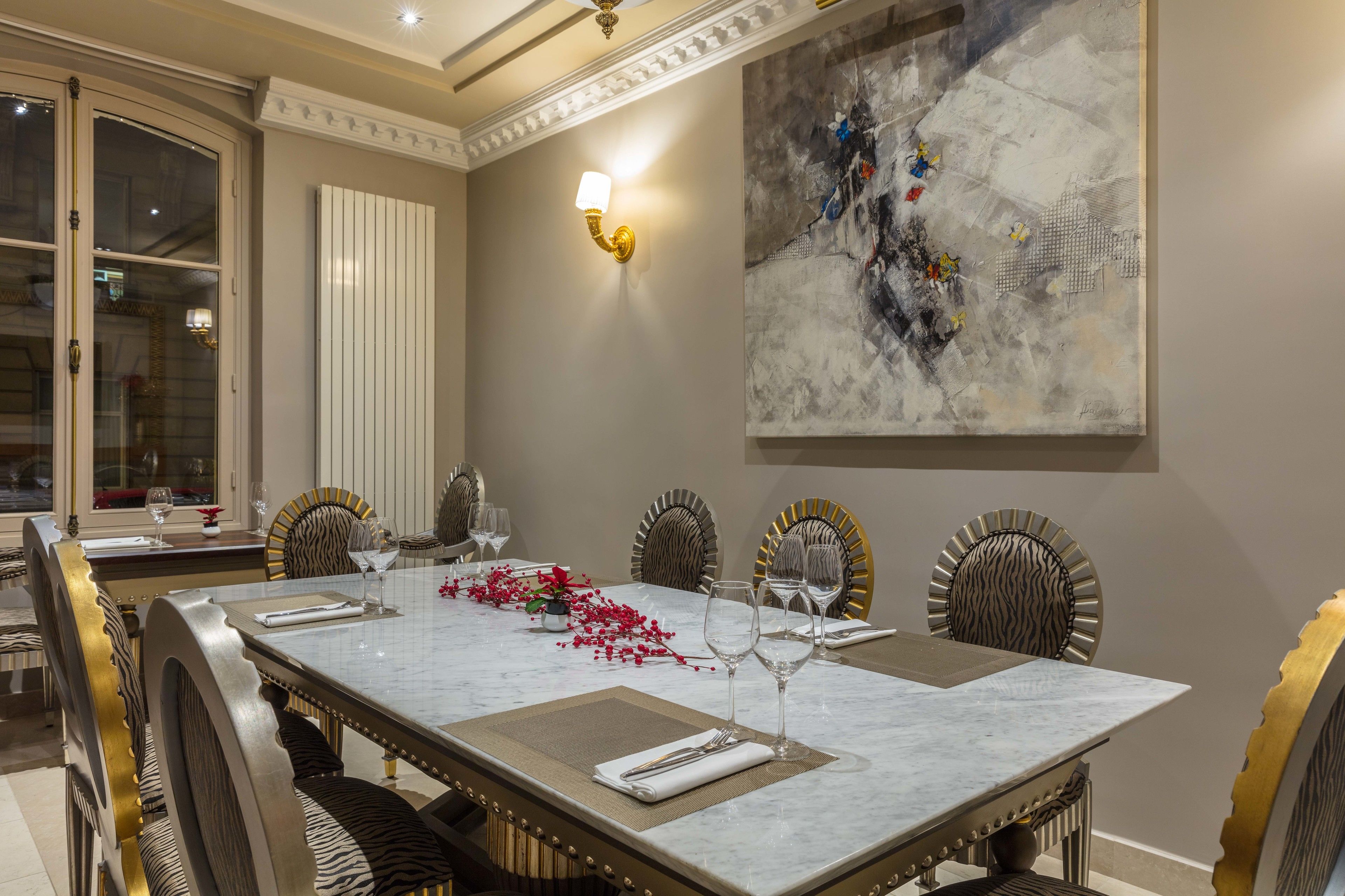 A dining area with a marble table, zebra-striped chairs, and a large abstract painting on the wall.