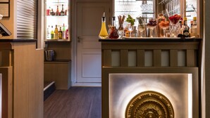 Een bar met flessen, glazen en een decoratieve lamp.