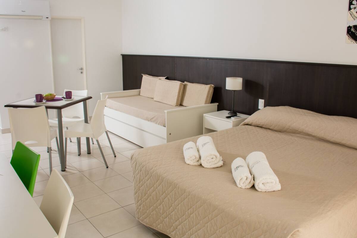 Una habitación de hotel con cama, escritorio, silla y mesita de noche.