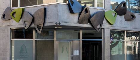 Fachada de un edificio con esculturas metálicas abstractas, ventanas grandes y un letrero que dice 'TORRE POTOSI'.