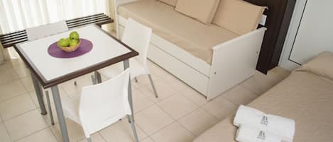 Habitación compacta con cama, sofá cama, una mesita con un frutero y una silla.