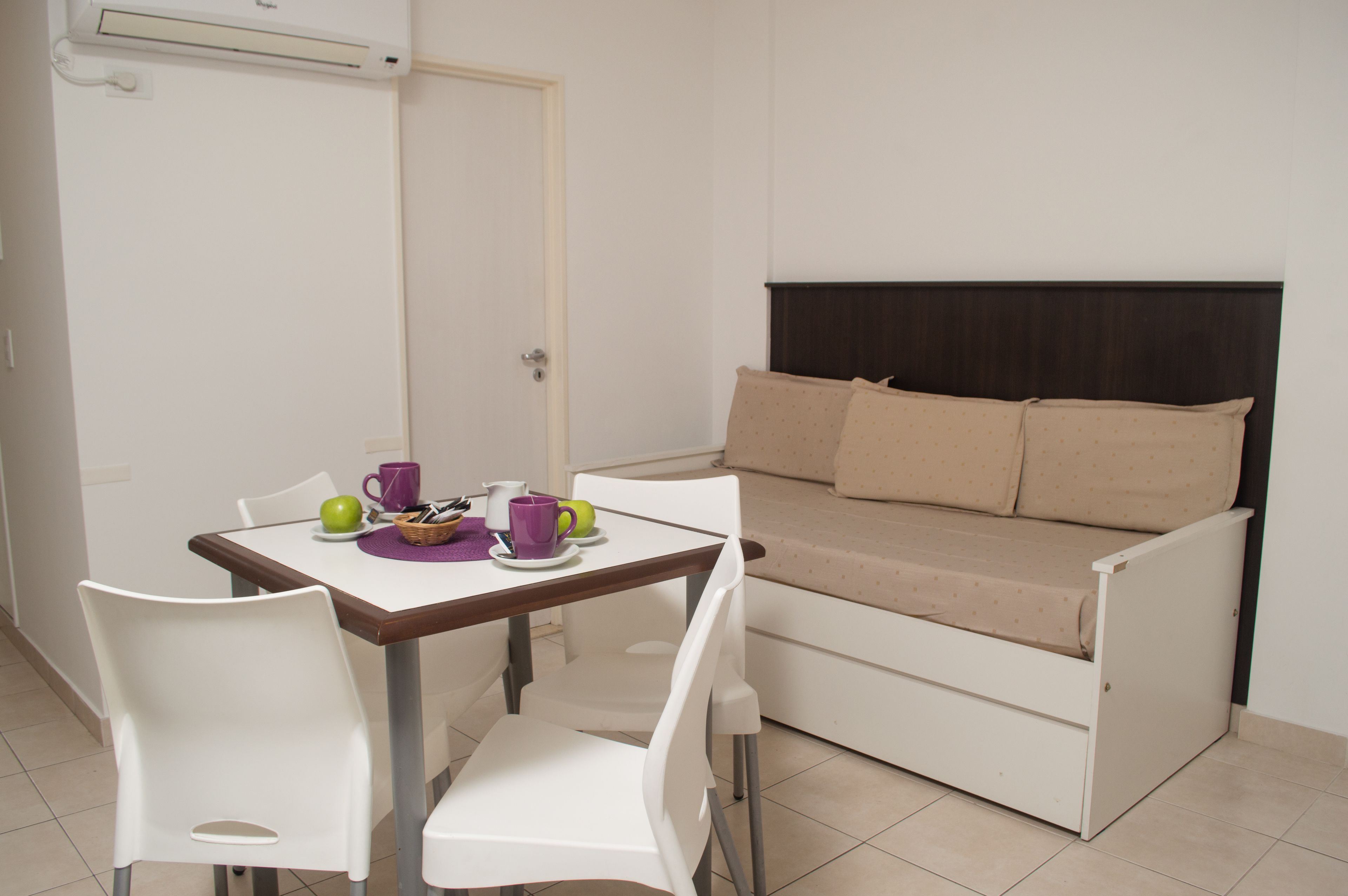 A small room with a bed, a table with chairs, and a door.
