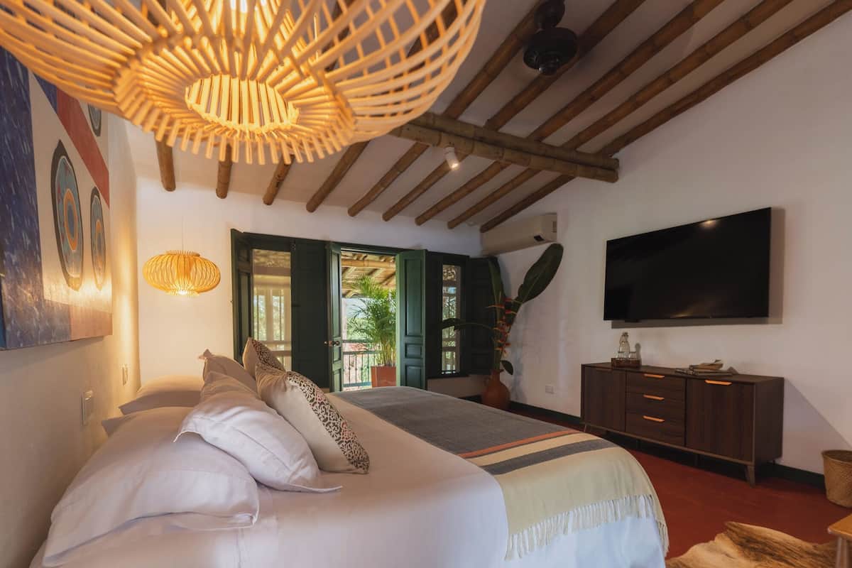 Une chambre à coucher comprenant un lit, un téléviseur, un plafond en bois et une porte donnant sur un espace extérieur.