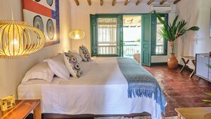 Een slaapkamer met een bed, een hanglamp, een plant in pot en een deur die leidt naar een balkon.