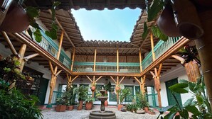 Een binnentuin met een fontein in het midden, omringd door plantenpotten en een houten balkonconstructie.