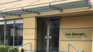 Entrada de un hotel con puerta de vidrio, una escalera y un letrero que dice "Los Sauces Apart Hotel".