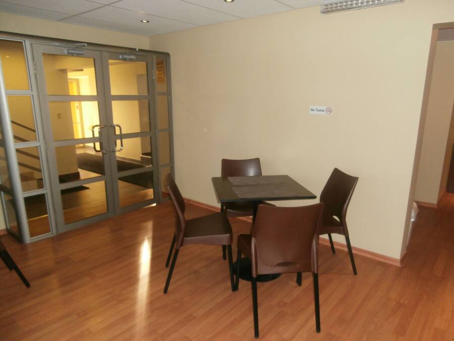 A dining area with a table and chairs, a sliding glass door, and a 'No Smoking' sign on the wall.