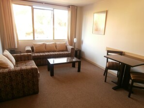 Una sala de estar con un sofá, una mesa de centro, una mesa de comedor y una silla.