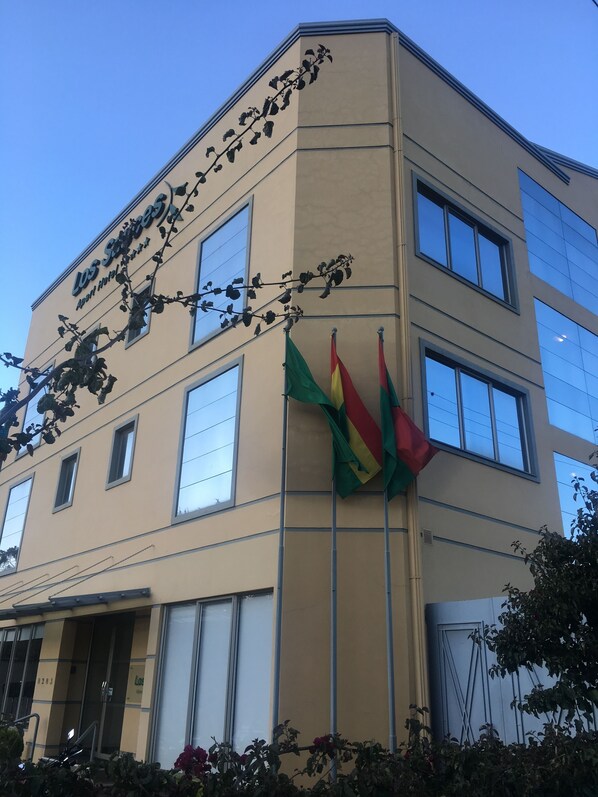 Un edificio con fachada color crema, varias ventanas y un letrero que dice 'Los Suites'.