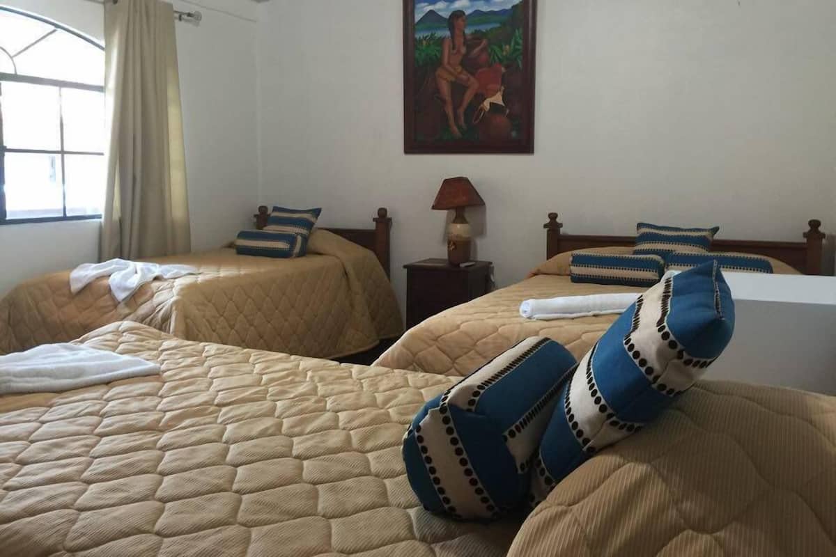 A hotel room with two beds, a painting on the wall, and a window with curtains.