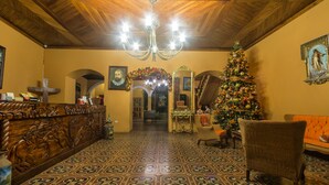 Vestíbulo de hotel con techo de madera, piso estampado, un árbol de Navidad y una recepción.