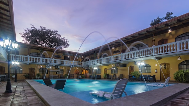 Un área de piscina con sillas de descanso y un porche cubierto.