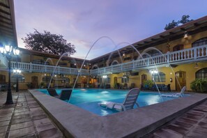 Un área de piscina con sillas de descanso y un porche cubierto.