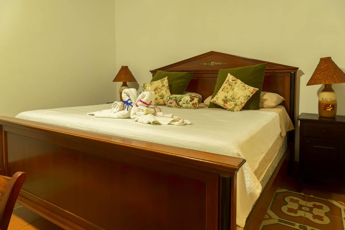 A neatly made bed with floral pillows, a wooden headboard, and two bedside lamps.