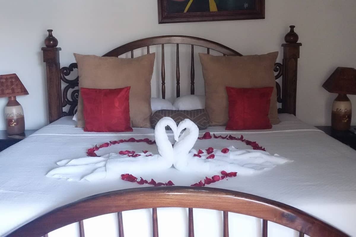 A bed with a swan-shaped arrangement of rose petals and a white swan centerpiece.