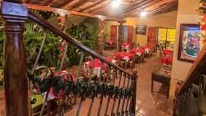 Un restaurante con vigas de madera, mesas rojas y decoración festiva.