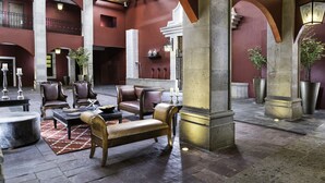 Un hall d’entrée spacieux, doté de fauteuils en cuir, d’une table basse et d’un tapis à motifs.