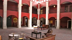 Un hall d’entrée spacieux avec de hauts plafonds, des murs rouges et plusieurs coins salon.