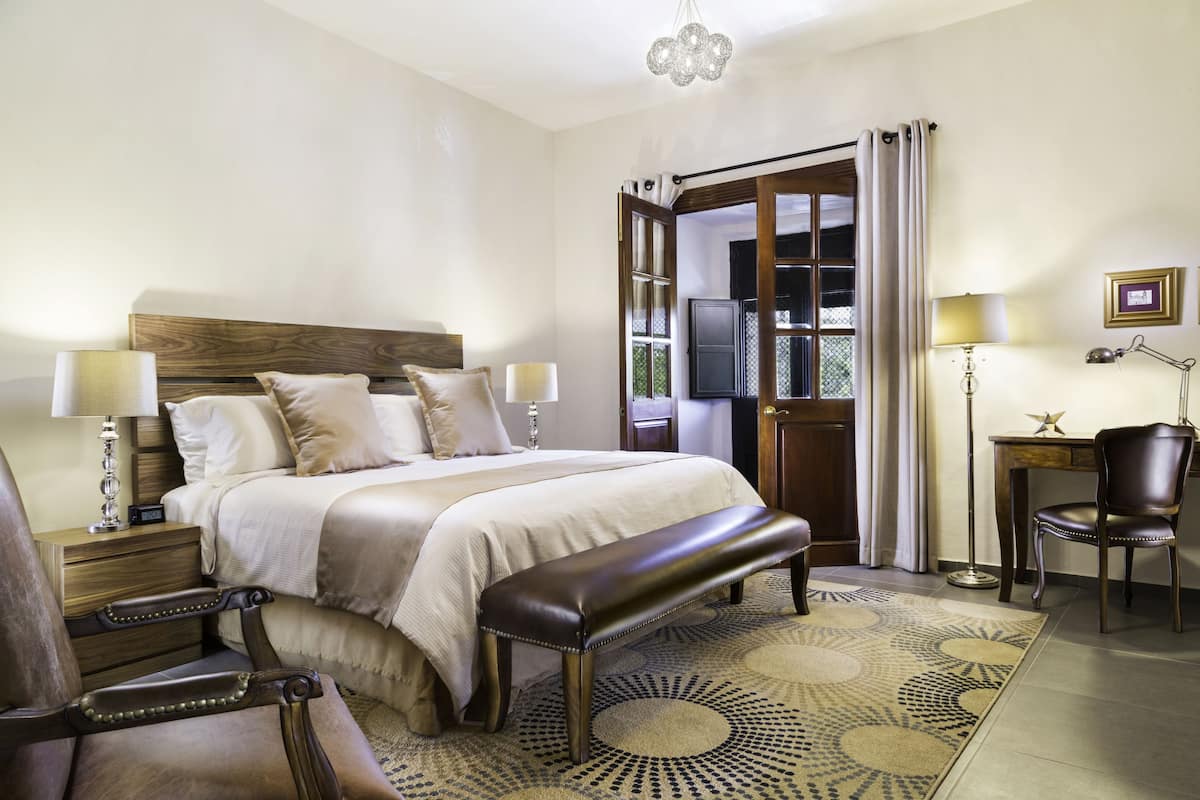 A well-appointed bedroom with a large bed, a bench, a desk, and a chair.