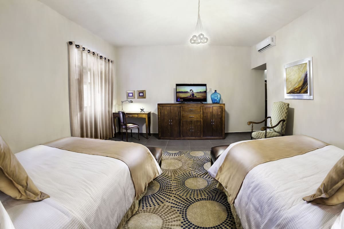 A hotel room with two beds, a television, a desk, and a cabinet.