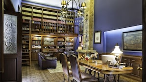 Une bibliothèque avec des étagères, un lustre, une table à manger et des fauteuils en cuir.