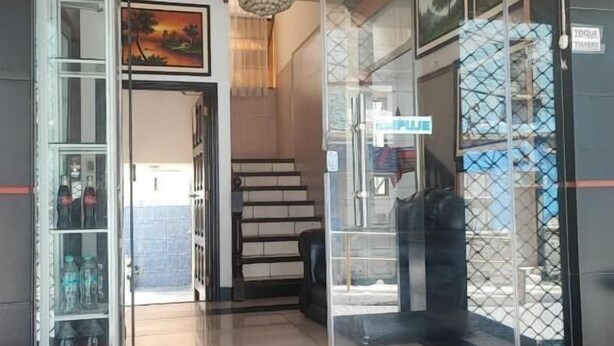 A hotel lobby with a tiled floor, a staircase, and a glass door with a sign. - Hotel Savoy  (La Paz)