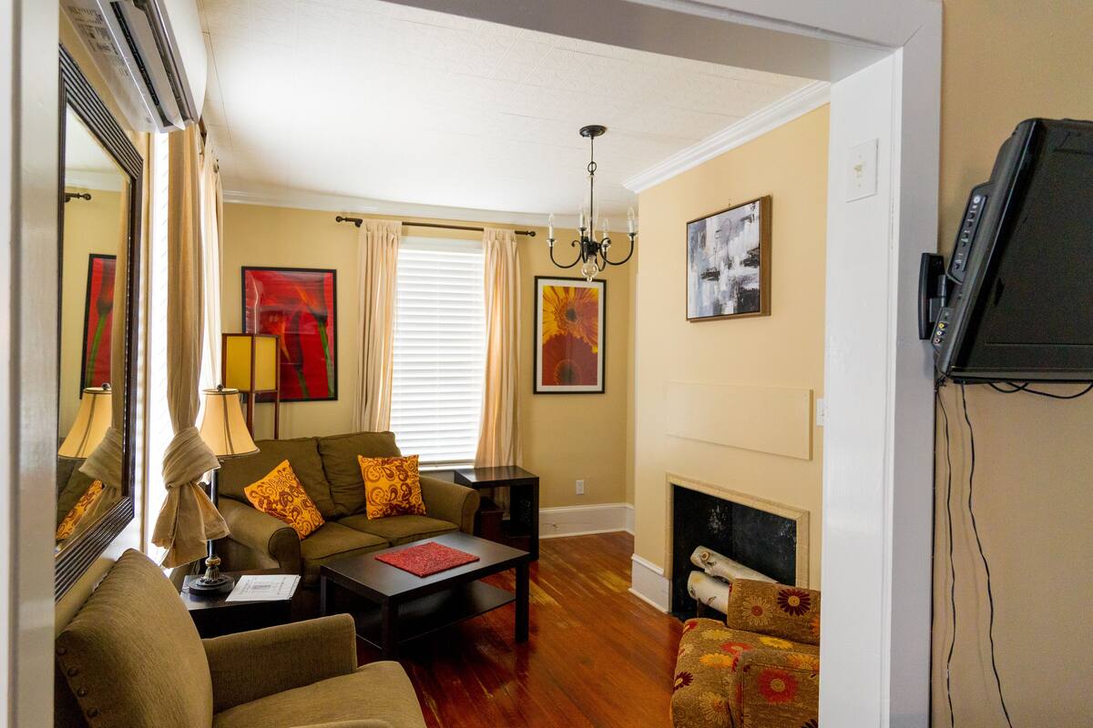 A living room with a sofa, armchairs, a coffee table, a fireplace, and a television.