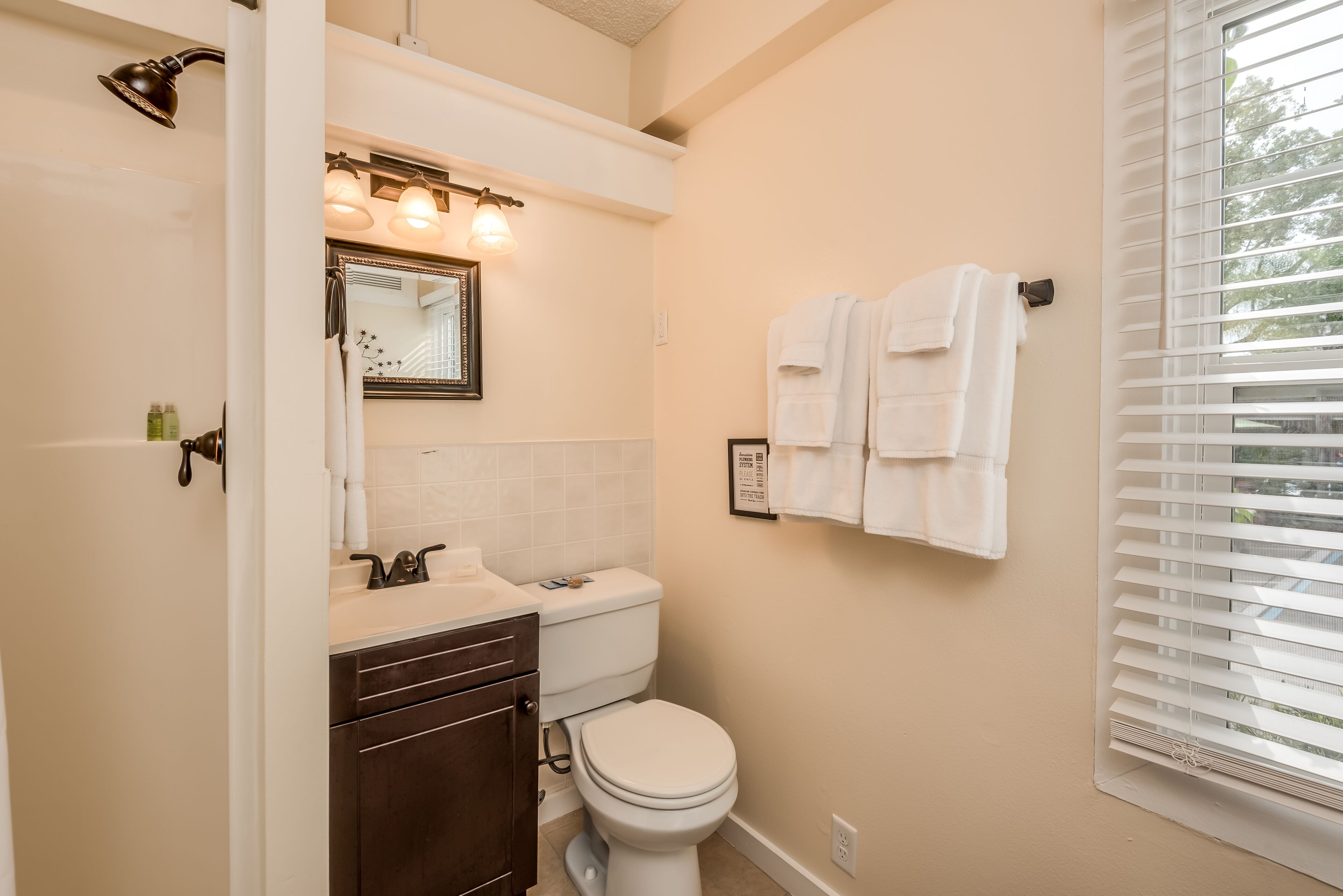 A bathroom with a toilet, sink, vanity, and a towel rack.