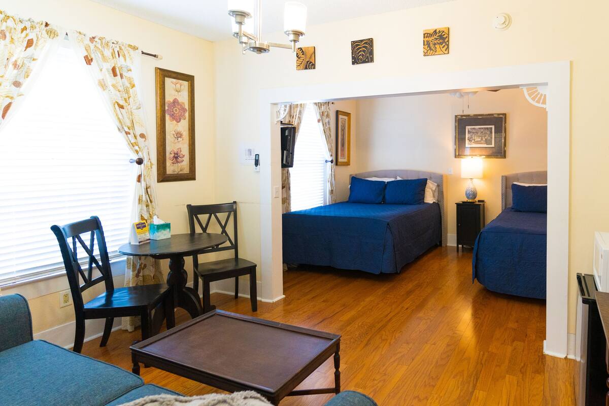 A compact room with a bed, a small table, a chair, and a sofa.