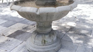 A stone fountain with multiple tiers, set on a paved patio. - The Heirloom Inn (Mount Dora)