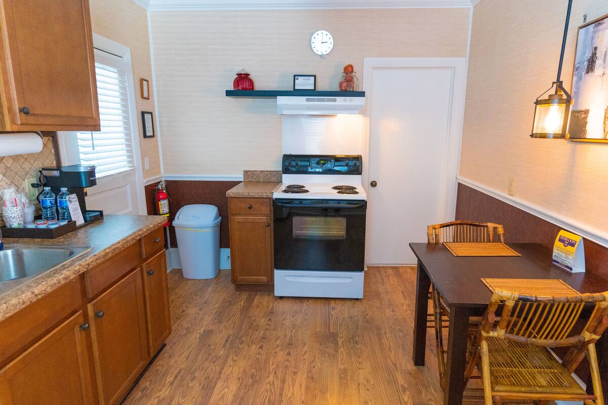 A compact kitchen with a stove, sink, and wooden cabinets.