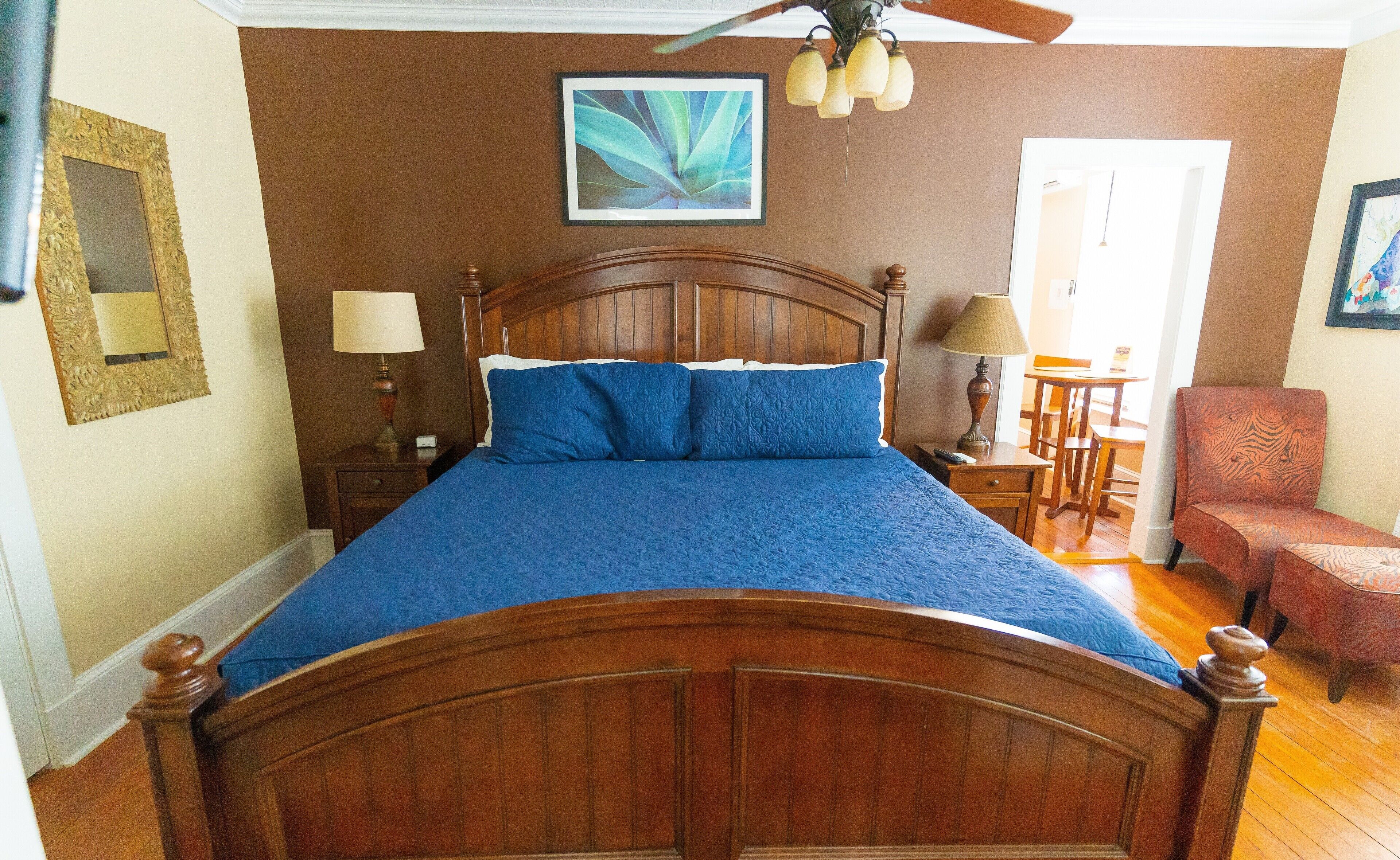 A bedroom with a wooden bed, two bedside tables, a chair, and a ceiling fan.
