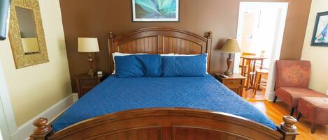 A bedroom with a wooden bed, two bedside tables, a chair, and a ceiling fan.