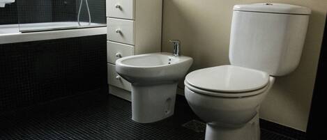 Un baño con inodoro, bidé y bañera.