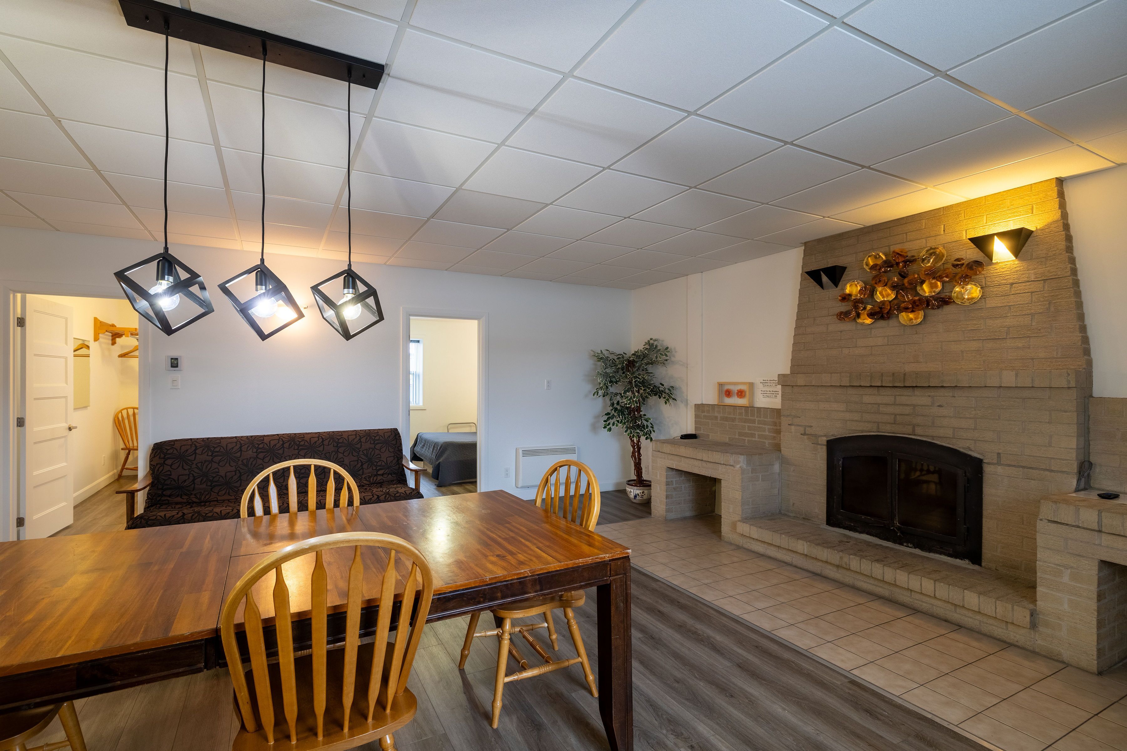 A dining area with a wooden table and chairs, a fireplace, and hanging pendant lights.