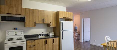 A kitchen with wooden cabinets, a white refrigerator, a stove, and a microwave.
