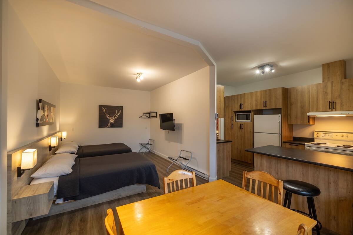 A compact room with a bed, a table, and a kitchenette.