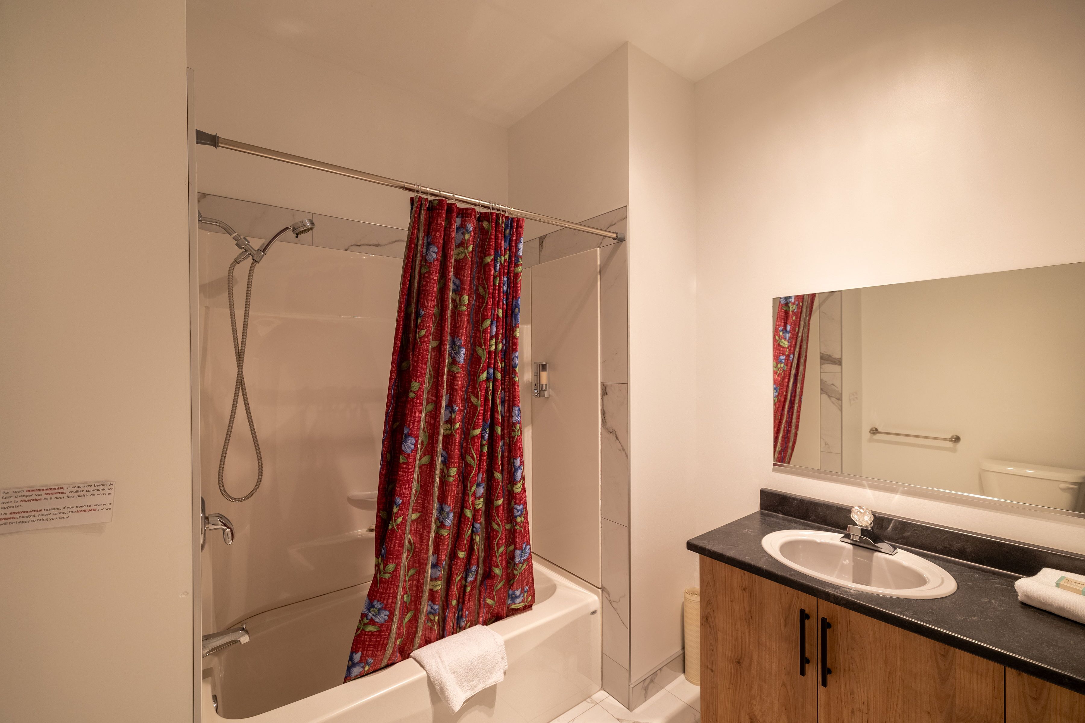 Un baño con ducha, bañera, lavamanos y espejo.
