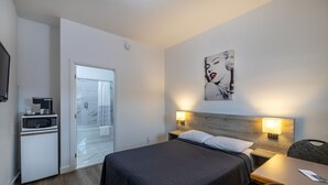 A hotel room with a bed, bedside table, chair, microwave, and a view of the outside.