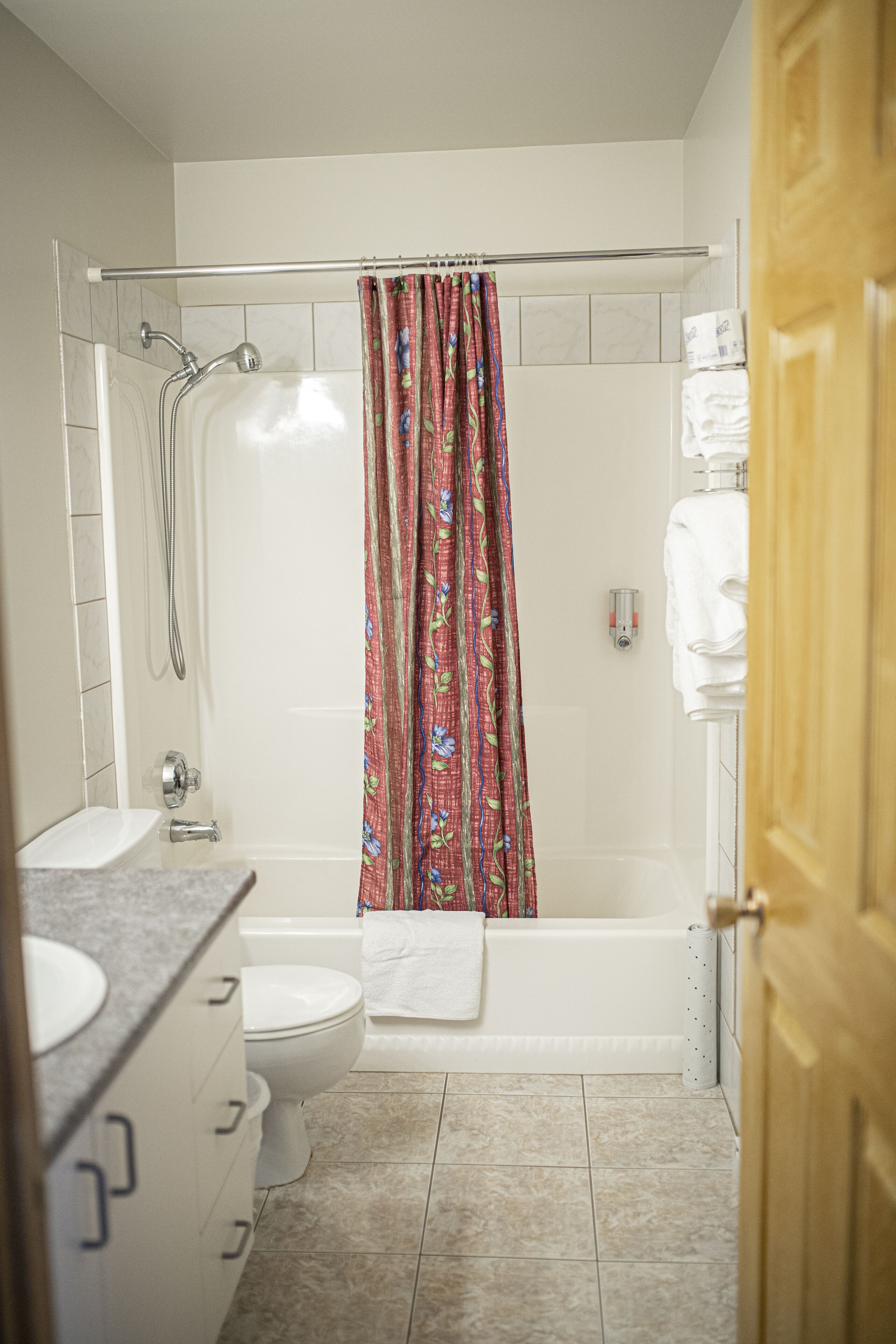 A bathroom with a shower, toilet, sink, and a towel rack.