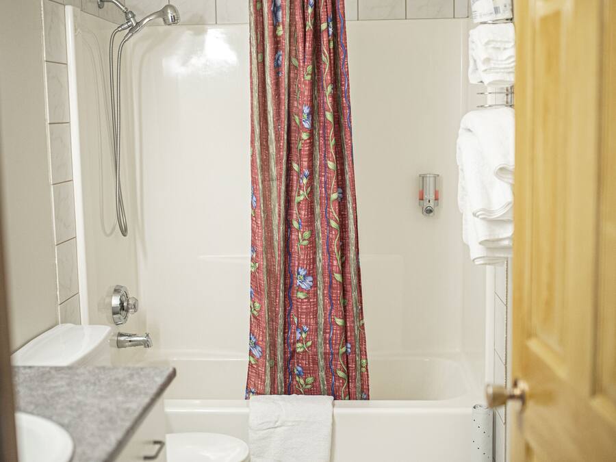 A bathroom with a shower, toilet, sink, and a towel rack.