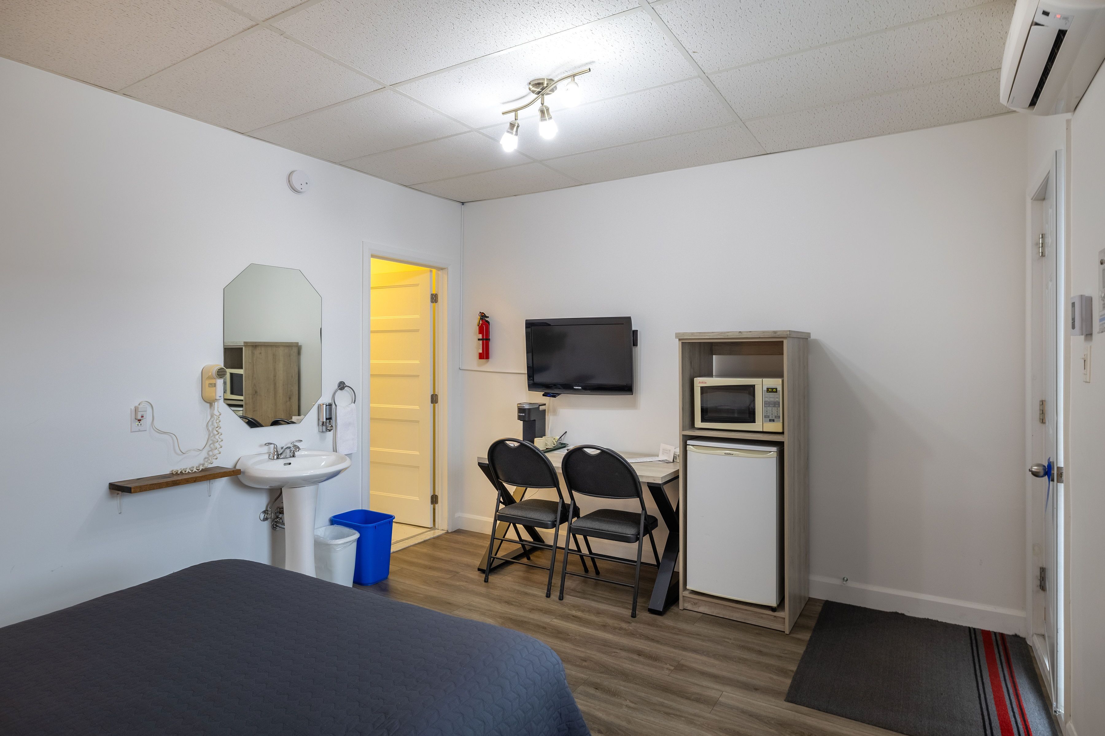 Hotelkamer met een bed, een bureau met stoel, een televisie, een magnetron en een kleine kitchenette.