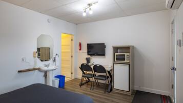 Hotelkamer met een bed, een bureau met stoel, een televisie, een magnetron en een kleine kitchenette.