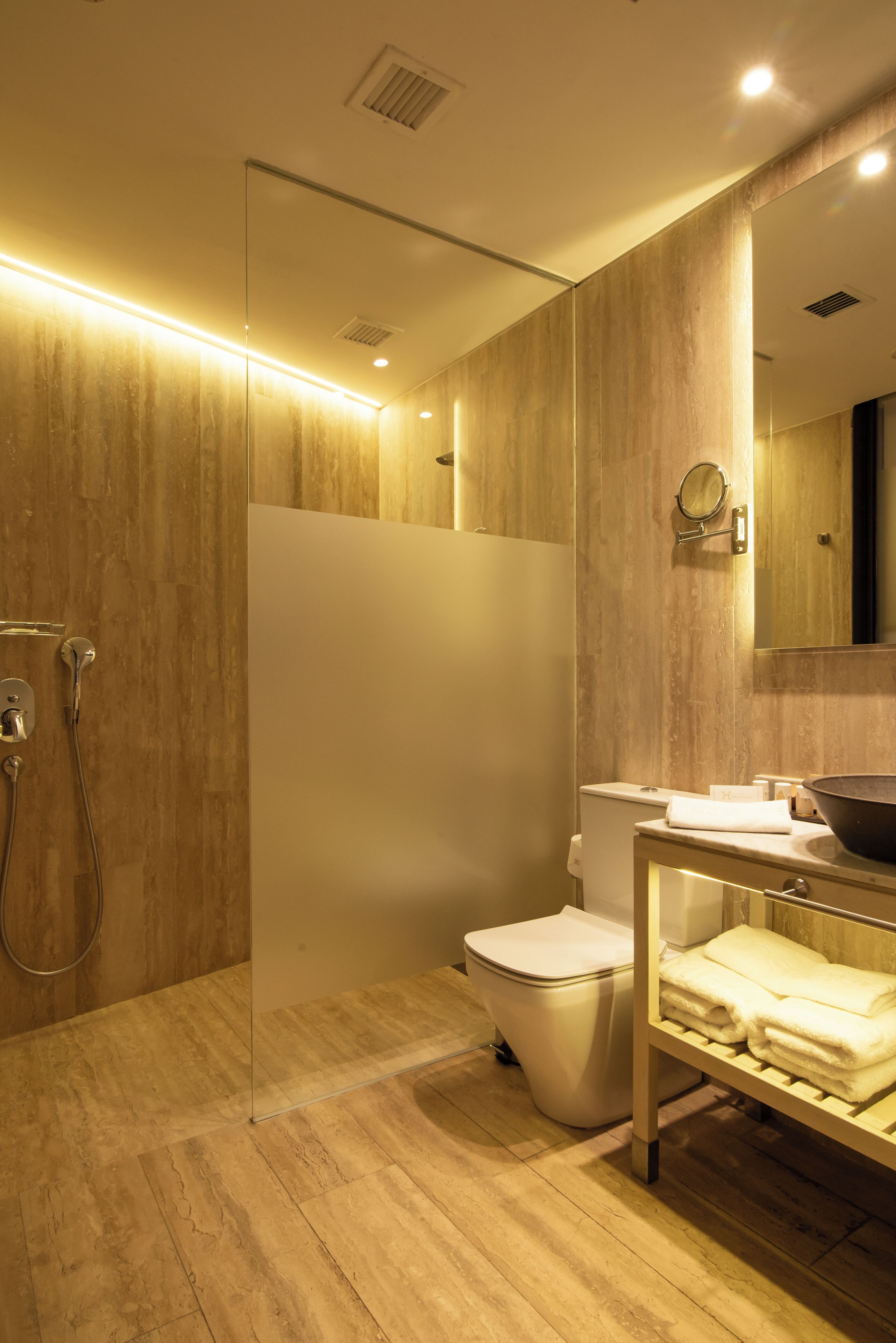 Un baño moderno con cabina de ducha de vidrio, inodoro y tocador con espejo.