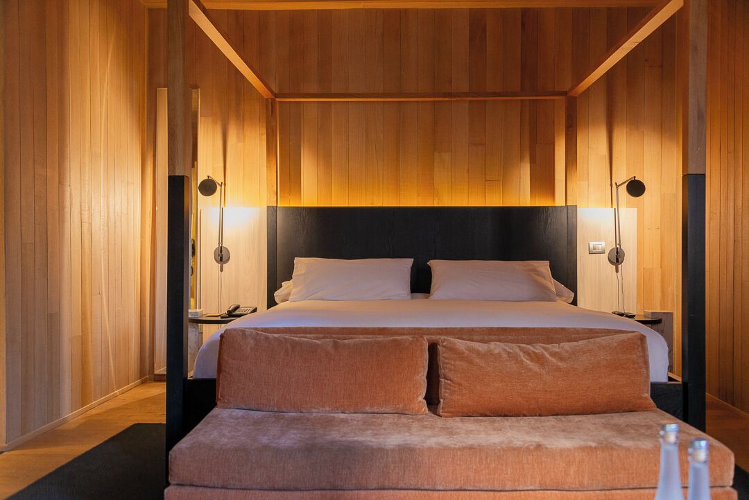 Un dormitorio con una cama grande, dos mesitas de noche y un banco al pie de la cama.