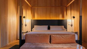 Un dormitorio con una cama grande, dos mesitas de noche y un banco al pie de la cama.