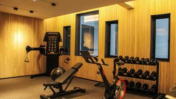 A gym with exercise equipment, including a bench, an elliptical, and a rack of dumbbells.