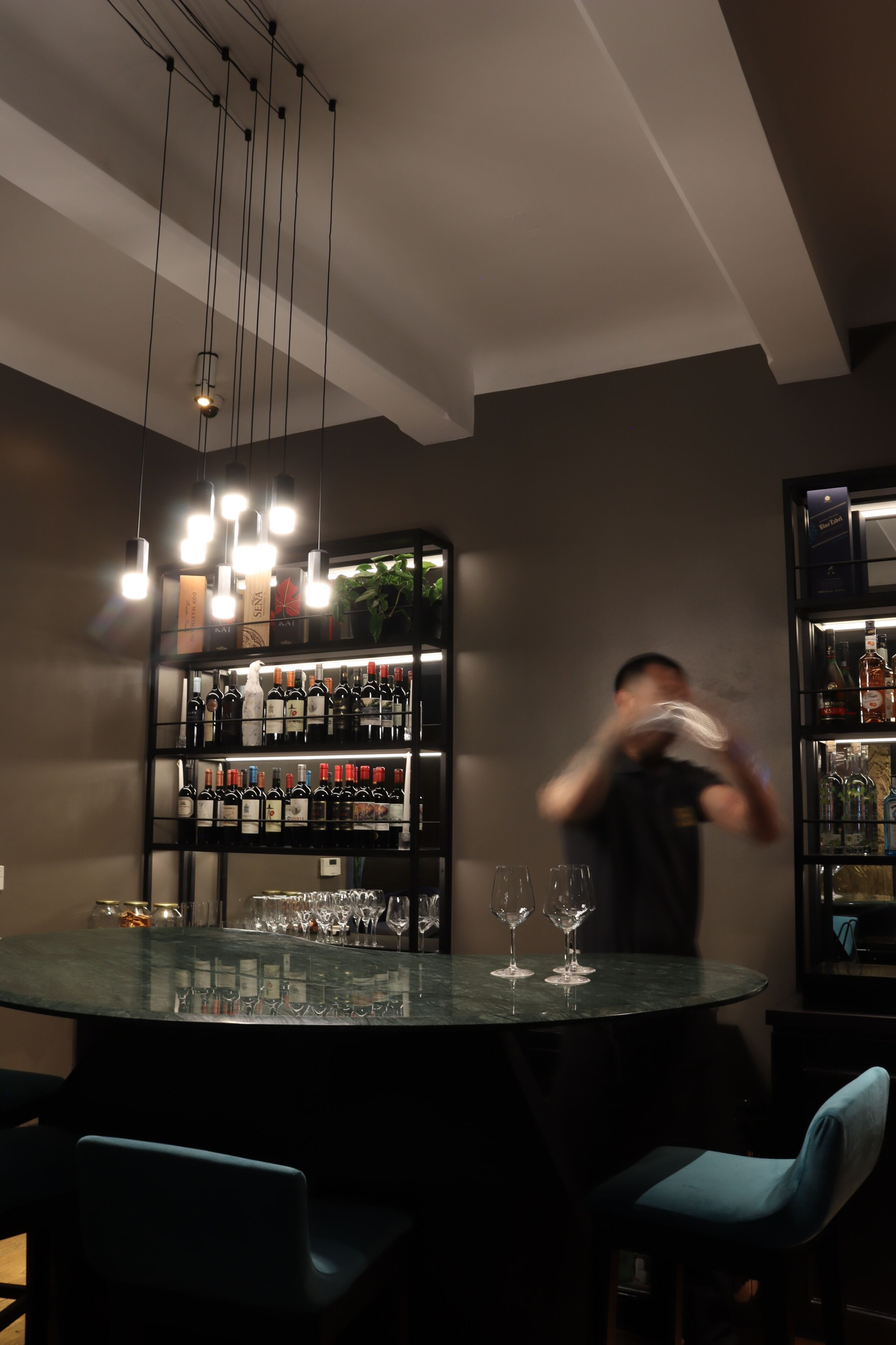 A bar area with a round table, chairs, and shelves of bottles.